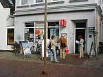 Touristinformation Eingang der Touristinformation mit Urlaubern, die sich die Aufsteller anschauen und nach Prospekten im aufgestellten Korb schauen.