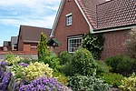 FeWo Luna Im Vordergrund ist ein Garten mit unten Blumen zu sehen. Das Haus ist ein Backsteinhaus